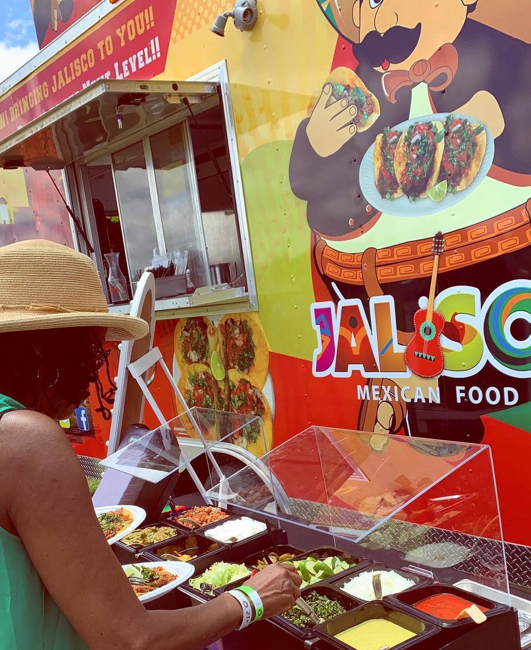 Guest serving herself from a Jalisco Food Truck taco bar at an outdoor event